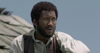 Movie still from “Free State of Jones” (2016), directed by Gary Ross – A man with a beard is standing outside; Close Up shot, Over the shoulder angle