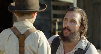 Movie still from “Free State of Jones” (2016), directed by Gary Ross – A man with a beard and a hat talking to another man; Close Up shot, Over the shoulder angle