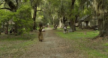 Movie still from “Free State of Jones” (2016), directed by Gary Ross – A woman walking down a dirt road in the woods; Extreme Wide shot, High angle