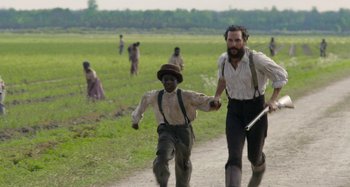 Movie still from “Free State of Jones” (2016), directed by Gary Ross – A man and a boy are walking down a dirt road; Medium shot, High angle