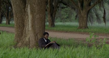 Movie still from “Free State of Jones” (2016), directed by Gary Ross – A man sitting under a tree reading a book; Wide shot, Over the shoulder angle