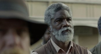 Movie still from “Free State of Jones” (2016), directed by Gary Ross – An older man with a beard and a mustache; Close Up shot, Over the shoulder angle