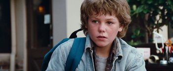 Movie still from “Free Willy” (1993), directed by Simon Wincer – A young boy with a blue backpack on his back; Close Up shot, High angle