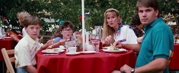Movie still from “Free Willy” (1993), directed by Simon Wincer – Two people sitting at a table with plates of food; Medium shot, High angle