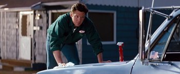 Movie still from “Free Willy” (1993), directed by Simon Wincer – A man in a green shirt is leaning over a car; Medium shot, Low angle