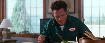 Movie still from “Free Willy” (1993), directed by Simon Wincer – A man sitting at a table with a plate of food; Medium shot, High angle