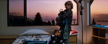 Movie still from “Free Willy” (1993), directed by Simon Wincer – A young boy holding a backpack in a bedroom; Wide shot, Low angle