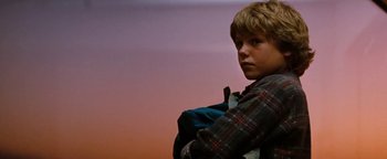 Movie still from “Free Willy” (1993), directed by Simon Wincer – A boy with a backpack standing in front of a sky background; Close Up shot, Low angle
