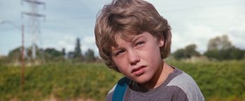 Movie still from “Free Willy” (1993), directed by Simon Wincer – A young boy with brown hair and a blue backpack; Close Up shot, Low angle