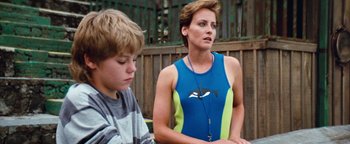 Movie still from “Free Willy” (1993), directed by Simon Wincer – A woman standing next to a young boy in front of a wooden fence; Medium shot, Over the shoulder angle