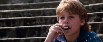 Movie still from “Free Willy” (1993), directed by Simon Wincer – A young boy is eating something while sitting on steps; Close Up shot, Low angle