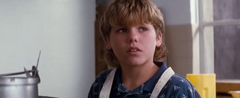 Movie still from “Free Willy” (1993), directed by Simon Wincer – A young boy with long blonde hair wearing a blue shirt; Close Up shot, Low angle