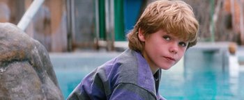 Movie still from “Free Willy” (1993), directed by Simon Wincer – A young boy sitting in front of a swimming pool; Close Up shot, High angle