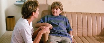 Movie still from “Free Willy” (1993), directed by Simon Wincer – Two young boys sitting in a chair talking to each other; Medium shot, Over the shoulder angle