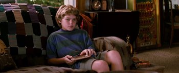 Movie still from “Free Willy” (1993), directed by Simon Wincer – A young boy sitting on a couch holding a nintendo wii game controller; Medium shot, High angle