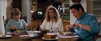 Movie still from “Free Willy” (1993), directed by Simon Wincer – A woman sitting at a table with a plate of food; Medium shot, High angle