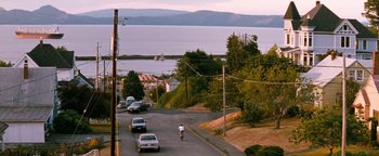 Movie still from “Free Willy” (1993), directed by Simon Wincer – A man riding a bike down the middle of a street; Extreme Wide shot, High angle