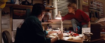 Movie still from “Free Willy” (1993), directed by Simon Wincer – Two people sitting at a table in front of a lamp; Wide shot, High angle