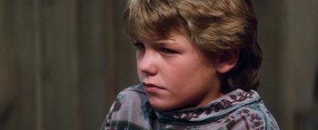 Movie still from “Free Willy” (1993), directed by Simon Wincer – A young boy is sitting down and looking at the camera; Close Up shot, High angle