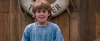 Movie still from “Free Willy” (1993), directed by Simon Wincer – A young boy standing in front of a life preserver; Close Up shot, High angle