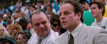 Movie still from “Free Willy” (1993), directed by Simon Wincer – A couple of men sitting next to each other in front of a crowd; Close Up shot, Low angle