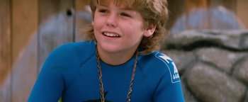 Movie still from “Free Willy” (1993), directed by Simon Wincer – A young boy wearing a blue shirt and a necklace; Close Up shot, High angle