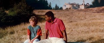 Movie still from “Free Willy” (1993), directed by Simon Wincer – Two young men sitting on the ground in a field; Medium shot, Over the shoulder angle