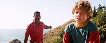 Movie still from “Free Willy” (1993), directed by Simon Wincer – A man giving a thumbs up to another man on top of a hill; Medium shot, Low angle
