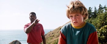 Movie still from “Free Willy” (1993), directed by Simon Wincer – A man and a boy standing next to each other on top of a hill; Medium shot, Low angle