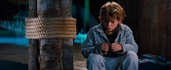 Movie still from “Free Willy” (1993), directed by Simon Wincer – A young boy sitting on the ground next to a rope; Medium shot, High angle