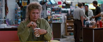 Movie still from “Free Willy” (1993), directed by Simon Wincer – A woman sitting at a table with a cup of coffee; Medium shot, Over the shoulder angle
