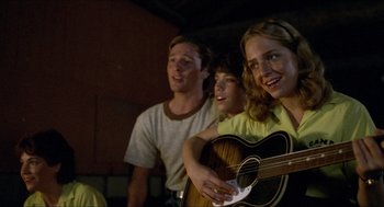 Movie still from “Friday the 13th” (1980), directed by Sean S. Cunningham – A group of people standing next to each other holding a guitar; Medium shot, Low angle