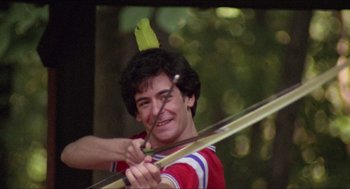 Movie still from “Friday the 13th” (1980), directed by Sean S. Cunningham – A young man wearing a hat while holding a bow and arrow; Medium shot, High angle