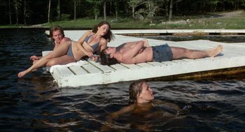 Movie still from “Friday the 13th” (1980), directed by Sean S. Cunningham – A group of people laying on a dock in the water; Wide shot, High angle