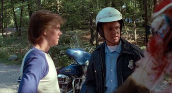 Movie still from “Friday the 13th” (1980), directed by Sean S. Cunningham – Two people standing next to each other near a motorcycle; Medium shot, Over the shoulder angle