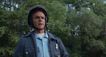 Movie still from “Friday the 13th” (1980), directed by Sean S. Cunningham – A man in a police uniform with a helmet on his head; Close Up shot, Low angle