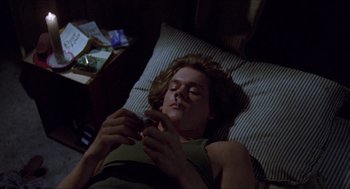 Movie still from “Friday the 13th” (1980), directed by Sean S. Cunningham – A woman laying in bed looking at her cell phone; Medium shot, High angle