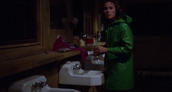 Movie still from “Friday the 13th” (1980), directed by Sean S. Cunningham – A woman wearing a green raincoat standing in front of a sink; Medium shot, Over the shoulder angle