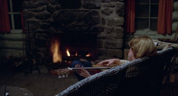 Movie still from “Friday the 13th” (1980), directed by Sean S. Cunningham – A woman sitting in front of a fireplace holding a guitar; Medium shot, High angle