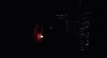 Movie still from “Friday the 13th” (1980), directed by Sean S. Cunningham – A person with a flashlight in the dark near a building; Extreme Wide shot, Low angle