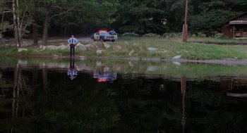 Movie still from “Friday the 13th” (1980), directed by Sean S. Cunningham – A man standing in the water next to a body of water; Extreme Wide shot, High angle