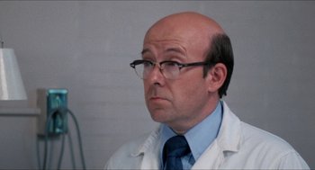 Movie still from “Friday the 13th” (1980), directed by Sean S. Cunningham – A man in a white lab coat and glasses; Close Up shot, Over the shoulder angle