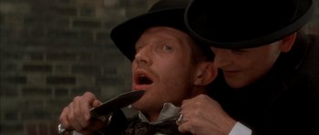 Movie still from “From Hell” (2001), directed by Allen Hughes – A man in a top hat is being shaved by another man in a top hat; Close Up shot, Overhead angle