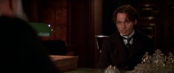 Movie still from “From Hell” (2001), directed by Allen Hughes – A man sitting at a table in front of a basket; Close Up shot, Over the shoulder angle