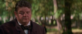 Movie still from “From Hell” (2001), directed by Allen Hughes – An older man in a suit and bow tie; Close Up shot, Over the shoulder angle