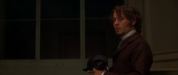 Movie still from “From Hell” (2001), directed by Allen Hughes – A man in a suit and tie holding a hat; Close Up shot, Over the shoulder angle