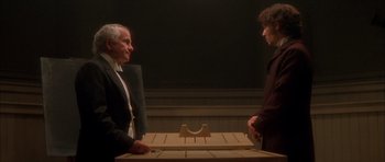 Movie still from “From Hell” (2001), directed by Allen Hughes – Two men standing in front of a wooden table; Medium shot, High angle