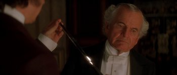Movie still from “From Hell” (2001), directed by Allen Hughes – An older man in a tuxedo holding a wand; Close Up shot, High angle