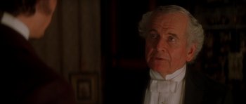 Movie still from “From Hell” (2001), directed by Allen Hughes – An older man in a white shirt and bow tie looking at the camera; Close Up shot, Over the shoulder angle