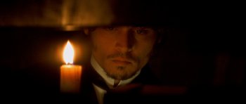 Movie still from “From Hell” (2001), directed by Allen Hughes – A person with a candle in the dark; Close Up shot, High angle